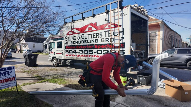 Gutters Tech technician installing a seamless aluminum downspout on a home in New Orleans, LA