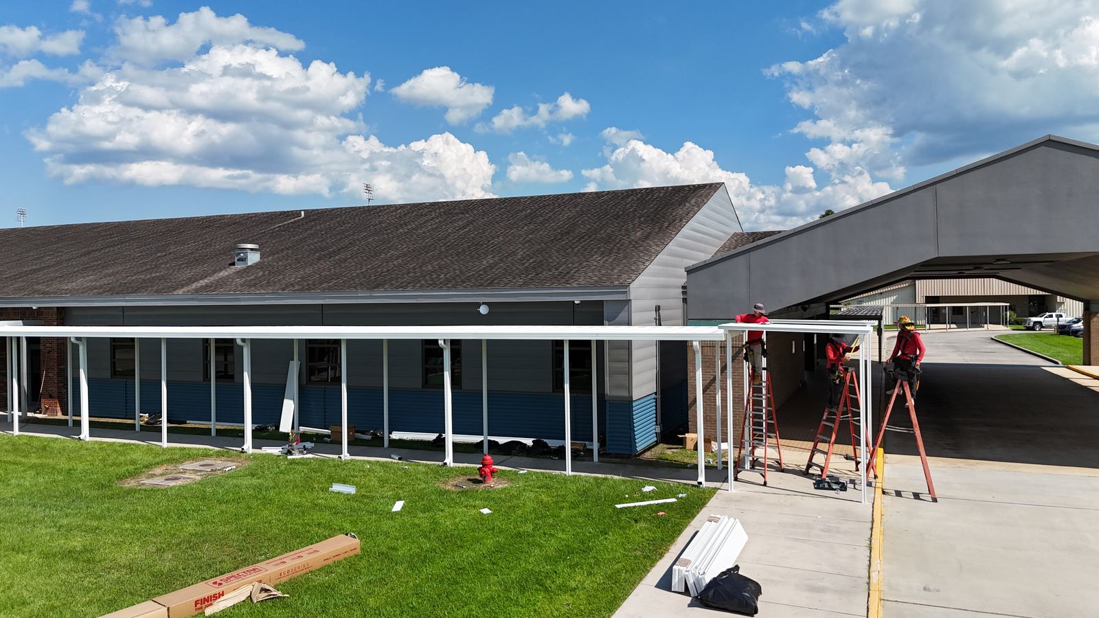 GuttersTech crew installing a gutter and covered walkway system along the roofline of a commercial building