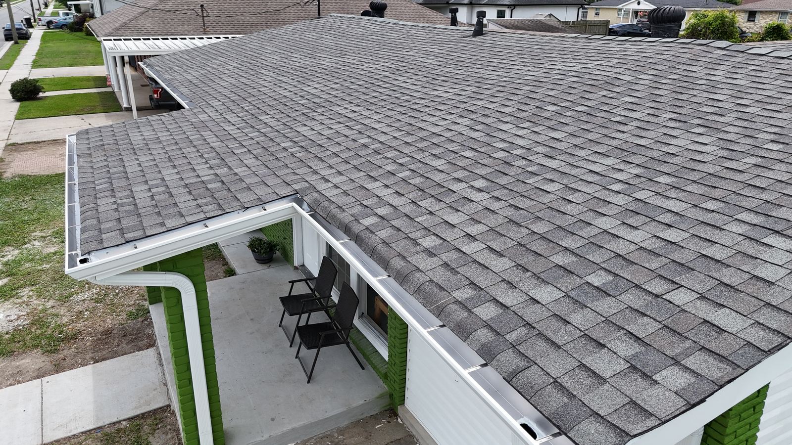 Aerial view of a completed architectural shingle roof replacement, including the gutters and a covered patio area