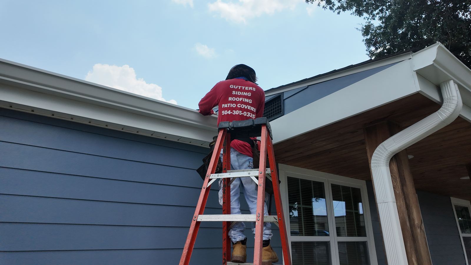 GuttersTech technician on a ladder working on gutters and siding, wearing a shirt listing the company's gutters, siding, roofing, and patio cover services
