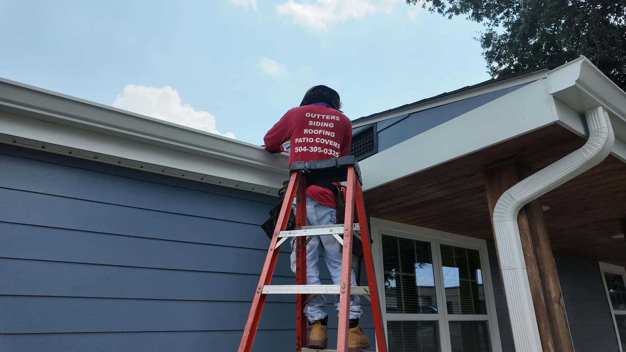 GuttersTech technician installing new HardiePlank lap siding board at the roofline of a New Orleans home