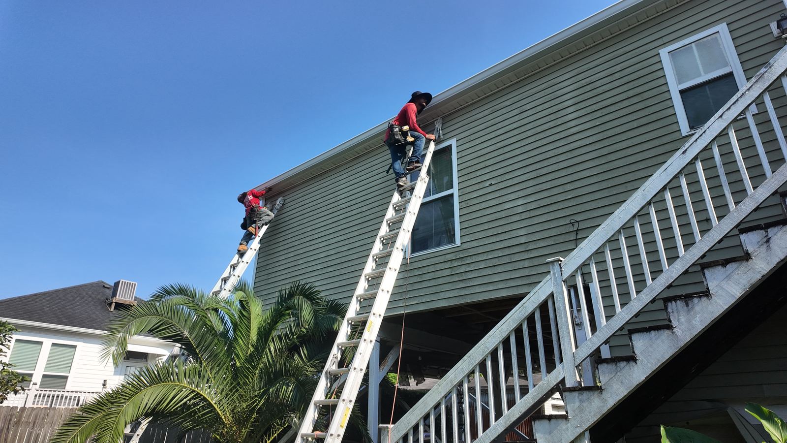 GuttersTech crew servicing lap siding on a raised New Orleans area home