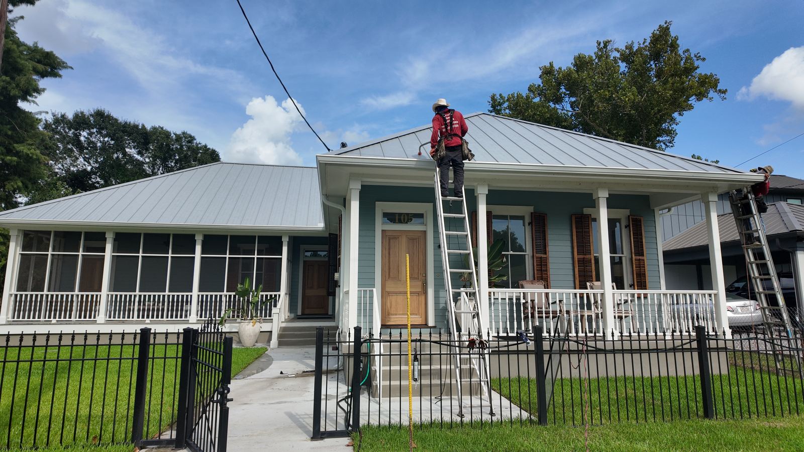 GuttersTech technician on a ladder servicing the gutter system of a raised cottage-style home typical of Old Metairie