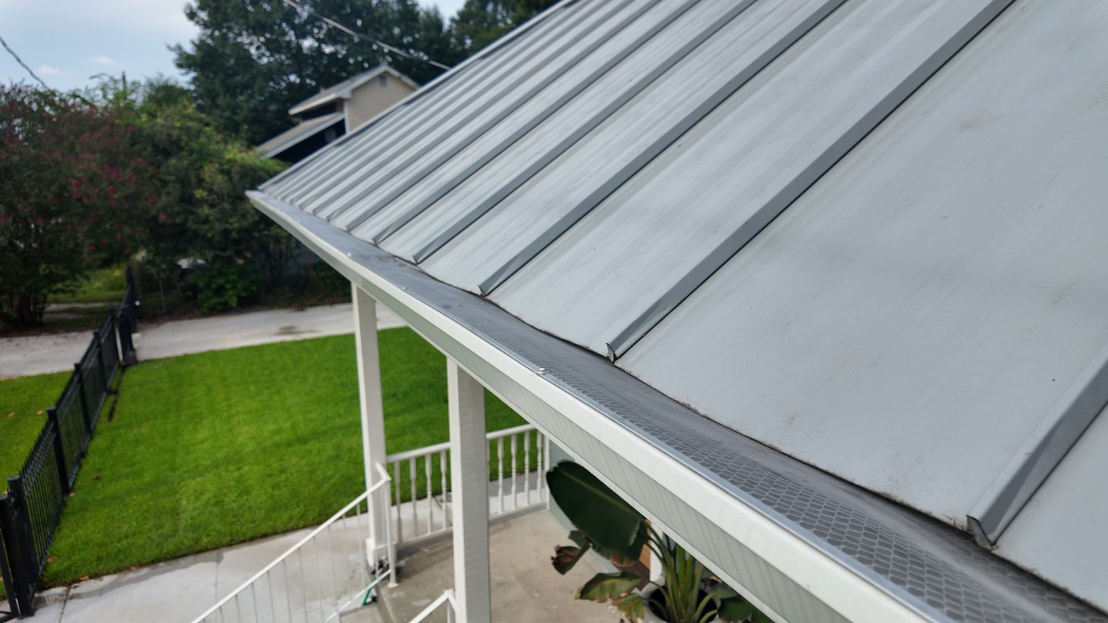 Close-up of a mesh-lined gutter fitted beneath a standing-seam metal roof edge