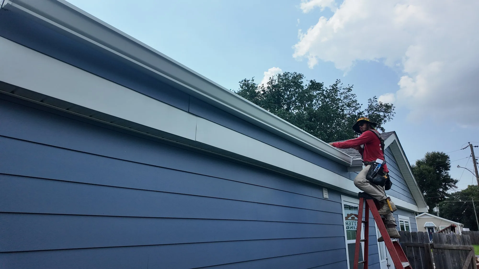 GuttersTech technician installing a vented soffit panel against new Hardie fiber cement siding