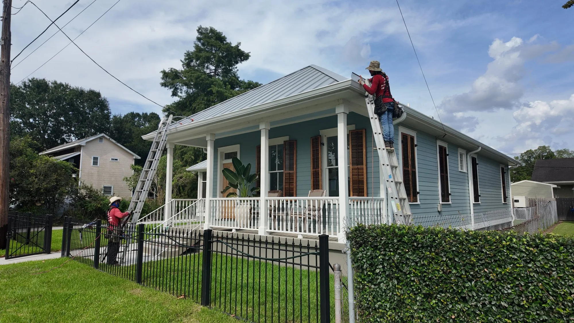 GuttersTech crew finishing a standing-seam metal roof on a raised New Orleans area cottage