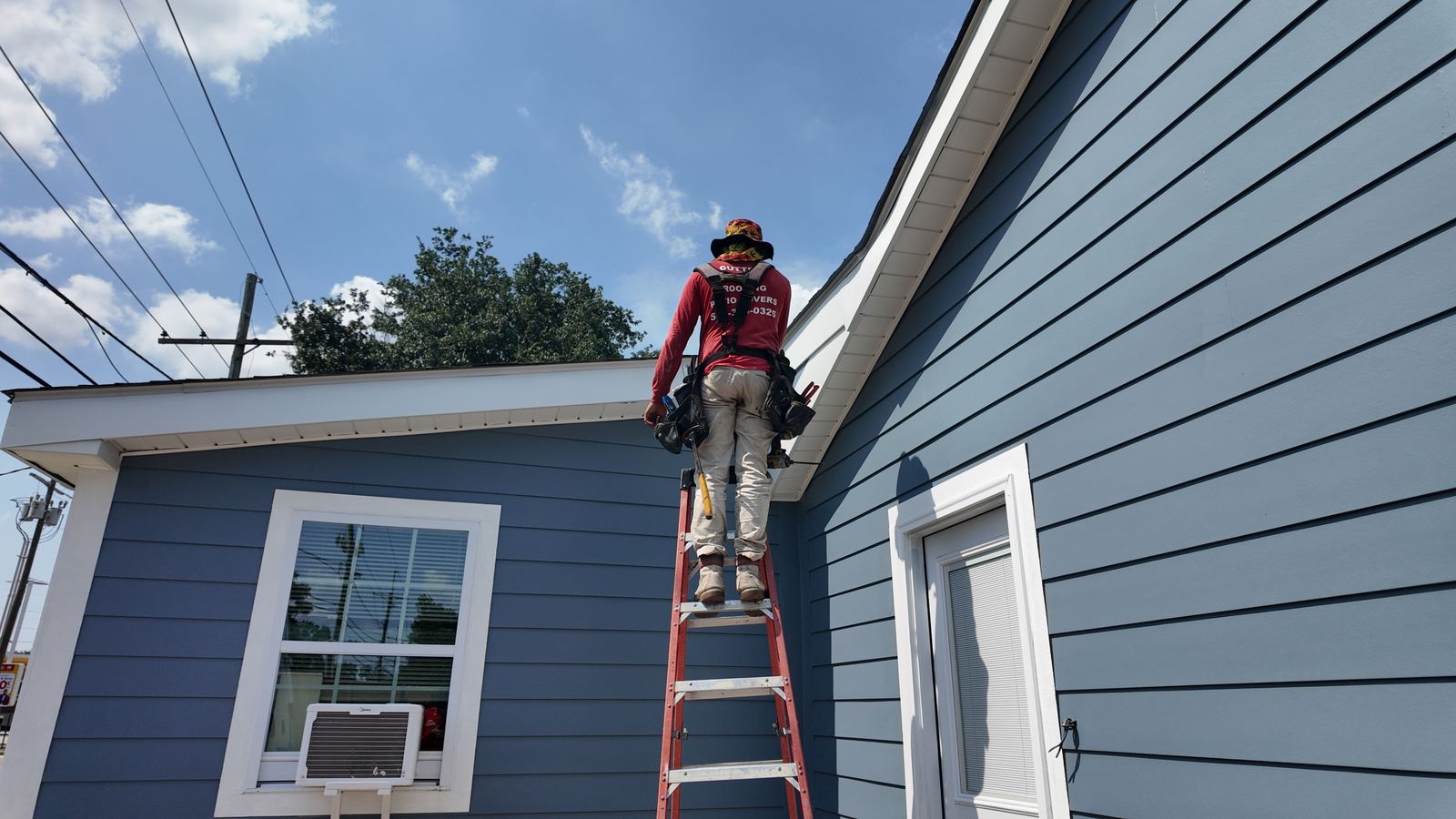 GuttersTech technician on a ladder servicing a home's gutter system